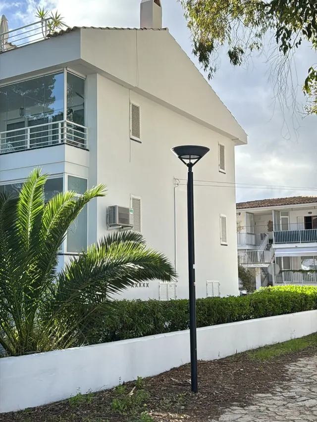 Edificio blanco con terraza, farola y palmera en primer plano