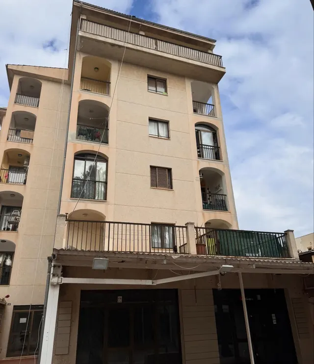 Edificio de cinco plantas en tono salmón con balcones, visto de frente
