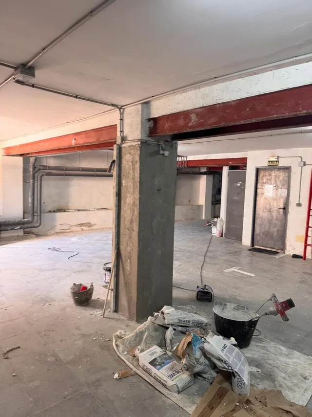Aparcamiento con el pilar reparado y materiales de obra en primer plano